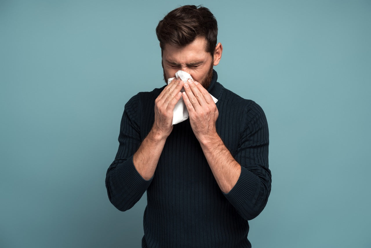 man covering his nose because of allergy